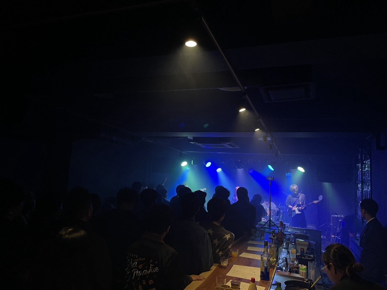 ライブ中の店内。青い照明の中、カウンター越しに演奏を観る客